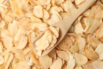 Dried garlic flakes and wooden scoop, top view