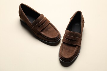 Fototapeta premium Pair of stylish brown loafer shoes on beige background, above view