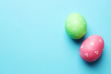 Painted Easter eggs on light blue background, flat lay. Space for text