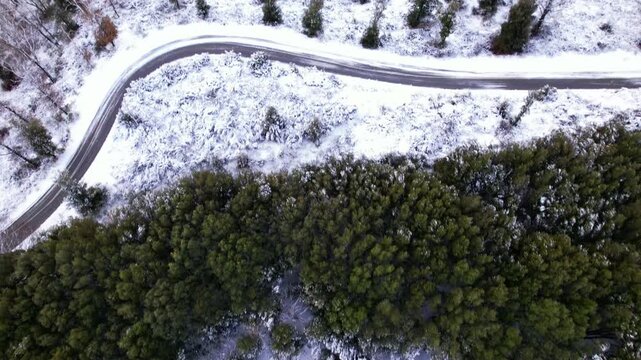 Drone video of a winding road. Aerial view of a winding mountain road in a winter forest.
A turn on a snowy forest road. A sharp turn on a mountain road among pine trees and white snow.