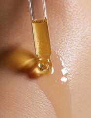 golden oil is pouring out of a glass dropper on dark skin, macro texture of the skin on which the oil is applied