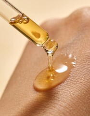 golden oil is pouring out of a glass dropper on dark skin, macro texture of the skin on which the oil is applied