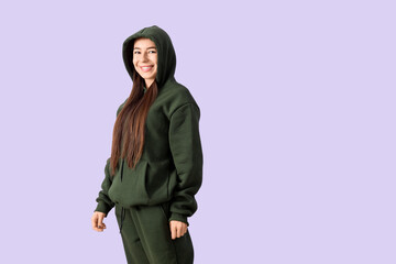 Fototapeta premium Young woman in khaki sports suit on lilac background
