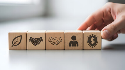 Hand places wooden block with shield dollar icon on row of blocks symbolizing security