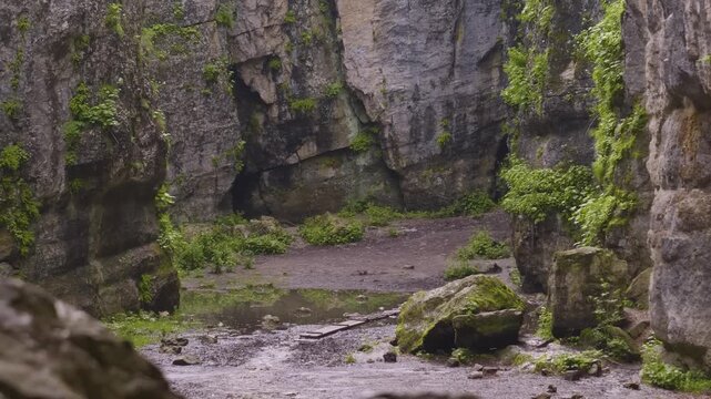 Footage capturing the breathtaking natural beauty of Matlas Canyon in the Republic of Dagestan, Russia. The scene showcases rugged, towering rock formations, lush green vegetation, a small stream, and