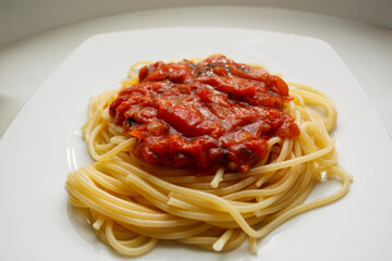 Homemade spaghetti pasta with red tomato bolognese sauce on a white plate. Classic Italian dinner...