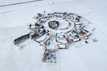 Aerial winter view of Gronowice, known as the Red Village, Poland. Snow-covered red rooftops and rural landscape captured by drone.