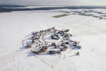 Aerial winter view of Gronowice, known as the Red Village, Poland. Snow-covered red rooftops and rural landscape captured by drone.
