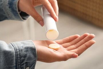 Woman taking vitamin C pills at home, closeup