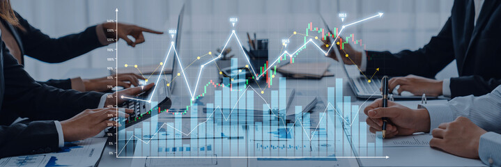 Business professionals engage in a data analysis meeting, utilizing laptops and graphs to discuss strategies and insights in a contemporary office setting. Scalp