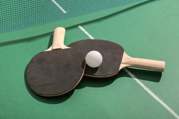 Ping pong rackets and ball near net on green table