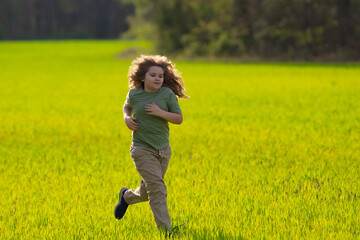 Fototapeta premium Child running in autumn field. Cute blonde kid run outdoors. Child on nature. Child in run motion on grass. Kid running at sun light. Teen running in meadow. Portrait of running child.
