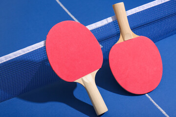 Ping pong rackets near net on blue table