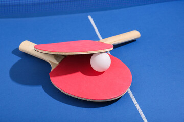 Ping pong rackets with ball on blue table