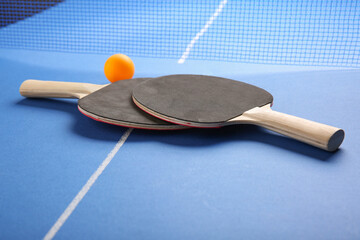 Ping pong rackets and ball on blue table