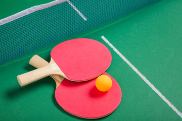 Ping pong rackets and ball near net on green table