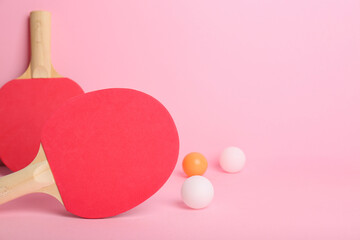 Red ping pong rackets and balls on pink background