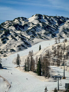 Alpine ski resort where white snow is tinted brown after African dust storm. Chairlifts, pistes, and rugged mountains illustrate unusual weather patterns and environmental change during late winter.