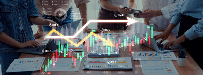 A dynamic business meeting showcasing collaboration and analysis of financial data with charts and graphs on laptops in a modern office setting. Scalp