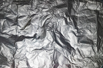 Primer plano de papel de aluminio arrugado mostrando superficie metálica con pliegues, dobleces y...