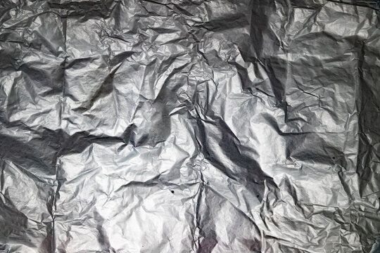 Primer plano de papel de aluminio arrugado mostrando superficie met&aacute;lica con pliegues, dobleces y reflejos.tensi&oacute;n y brillo, simbolizando fragilidad, transformaci&oacute;n y materialidad industrial.
