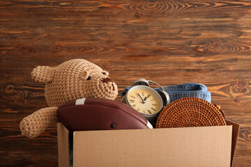 Box of unwanted stuff for yard sale on brown wooden background © Pixel-Shot