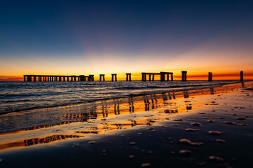 Plage de Fort Myers au coucher de soleil avec vue sur le vieux ponton et son reflet, jolis rayons...
