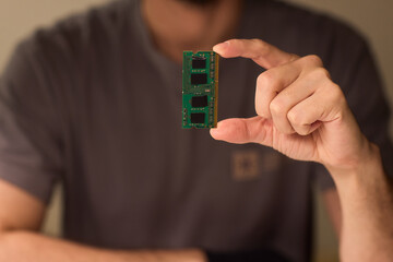 Individual carefully inspecting SODIMM memory module in detailed review, Technician performing detailed visual assessment of RAM stick with neutral lighting and focused attention