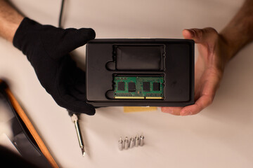 Detailed shot capturing repair process of computer memory components, Technician carefully handling SODIMM memory module while performing technical diagnostic procedures