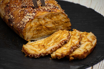 Vegan seitan roast- spicy wheat gluten as meat protein alternative, sliced on slate board