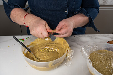 Confectioner chopping pistachios to put in the cream in the bowl.