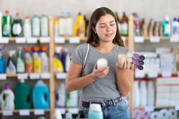 Young woman buyer chooses scented candles in household chemicals store