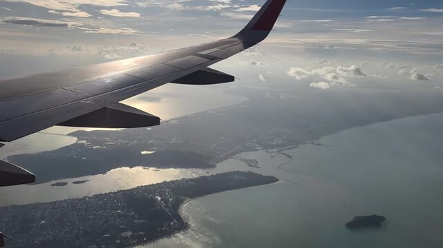 The plane was flying over Songkhla, Thailand. Aerial view of the Songkhla city the wing tips of the airplane looking downwards to the city.
