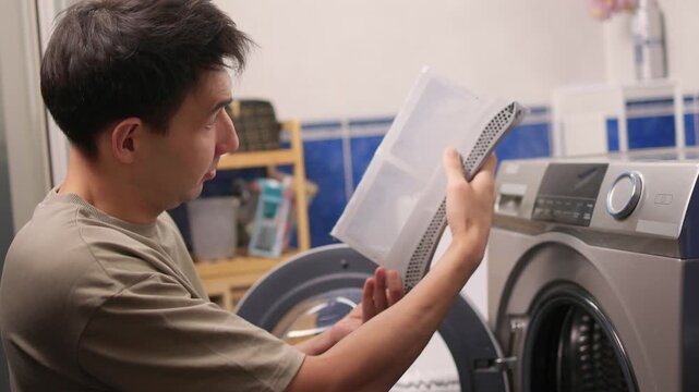 Technician examining dryer lint screen thoroughly, Detailed scene of maintenance technician carefully assessing lint filter inside frontload dryer in laundry room setting
