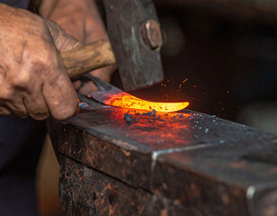 A closeup of a skilled blacksmiths hands hammering redhot metal on an anvil. This dramatic image shows sparks flying and represents hard work, tradition, and industrial craftsmanship.