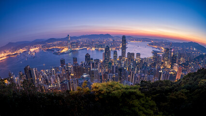 Fototapeta premium HongKong skyline at blue hour overlooking harbor, panoramic cityscape with glowing lights and dramatic twilight sky 