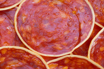 Obraz premium Spicy meat slices, Closeup of seasoned chorizo slices with cheese and paprika shine, Detailed view of overlapping spicy sausage rounds with cheese on textured surface