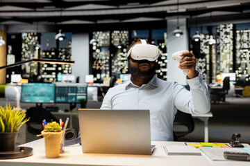 Black male office worker using AI tools with VR after hours at desk, working hard in the office with virtual reality headset to ensure fact checking and forecasting projections. Strategy room.