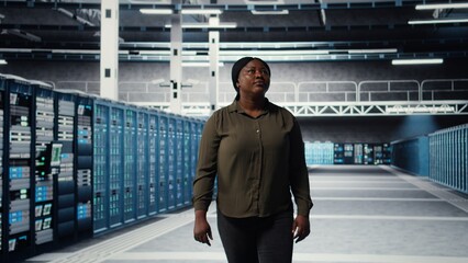 Engineer walking in data center, checking hardware for system stability. Employee overseeing server farm rigs, configuring infrastructure to optimize performance, camera A