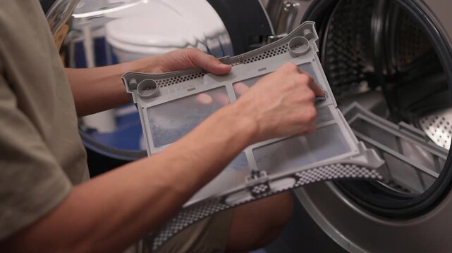 Technician examining dryer lint screen thoroughly, Detailed scene of maintenance technician carefully assessing lint filter inside frontload dryer in laundry room setting