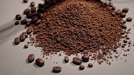 Close-up shot of ground coffee and beans on a white surface. The overhead angle captures texture, ideal for a coffee-themed video background.