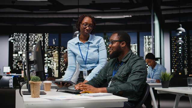 Business manager and assistant monitoring data analytics in dark office, utilizing reports and insights to plan forecast for performance metrics and statements. Goal setting late at night. - Powered by Adobe