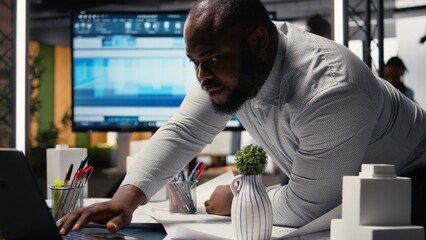 Black real estate developer does city planning with architectural sketch and 3D models for a new residential area construction project layout. Contractor expert ensures site preparation.