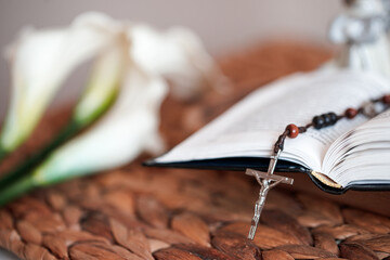 Open Catholic Bible and rosary on a wooden table