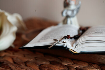 Open Catholic Bible and rosary on a woven surface