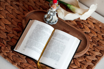Open Catholic Bible on table with candle and flower