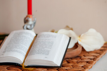 Open Catholic Bible on a woven mat with candle and flower