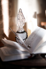 Religious statue and open Catholic Bible in warm light