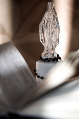 Crystal figure on a prayer Catholic Bible with rosary beads