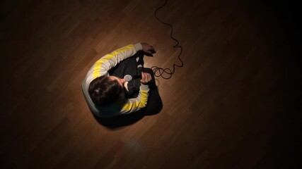 Comedian performing stand up comedy, holding a microphone on a wooden stage, with a spotlight illuminating the speaker from above, creating an atmosphere of entertainment and performance